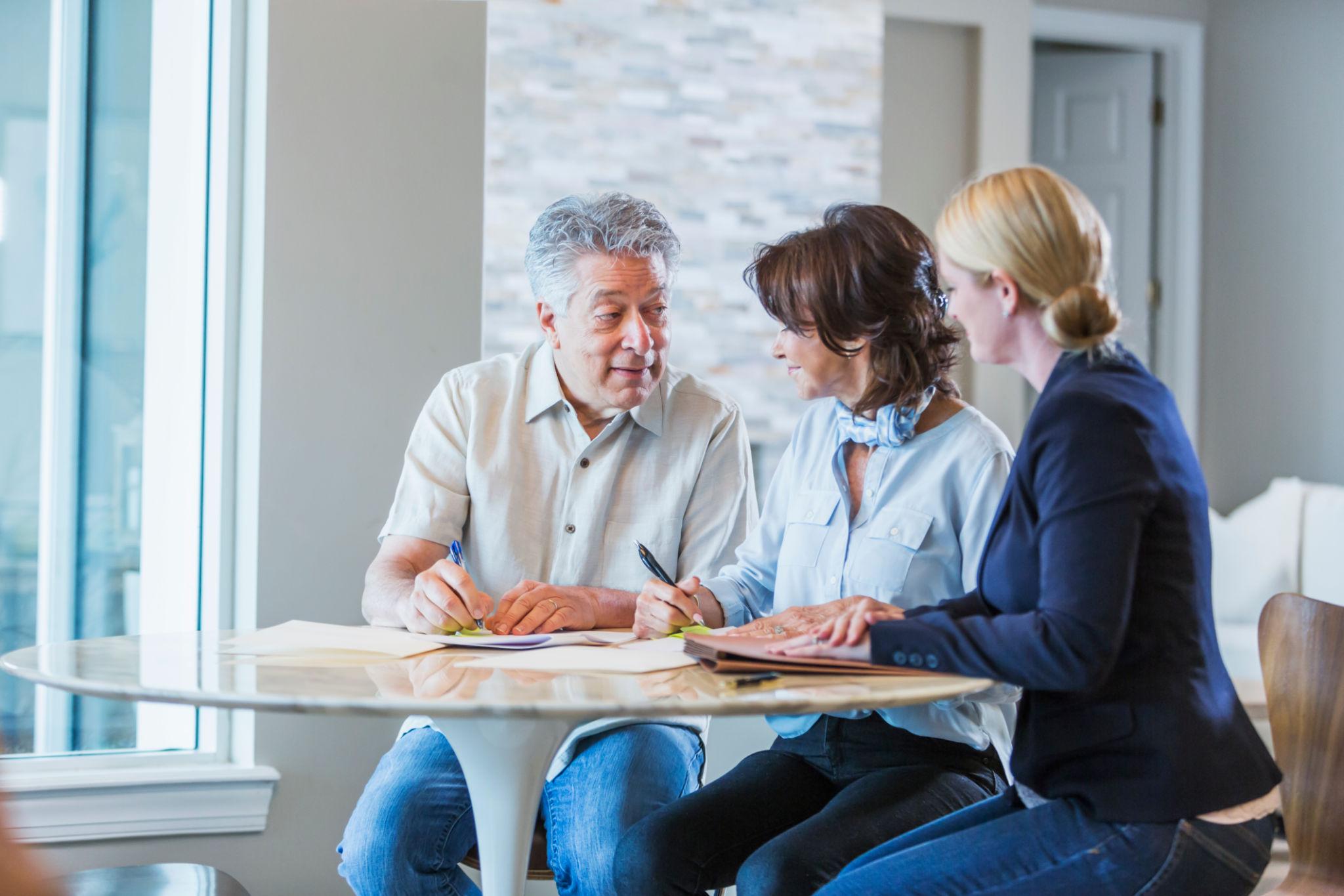 Senior homeowners reviewing long-term care and retirement planning documents at home